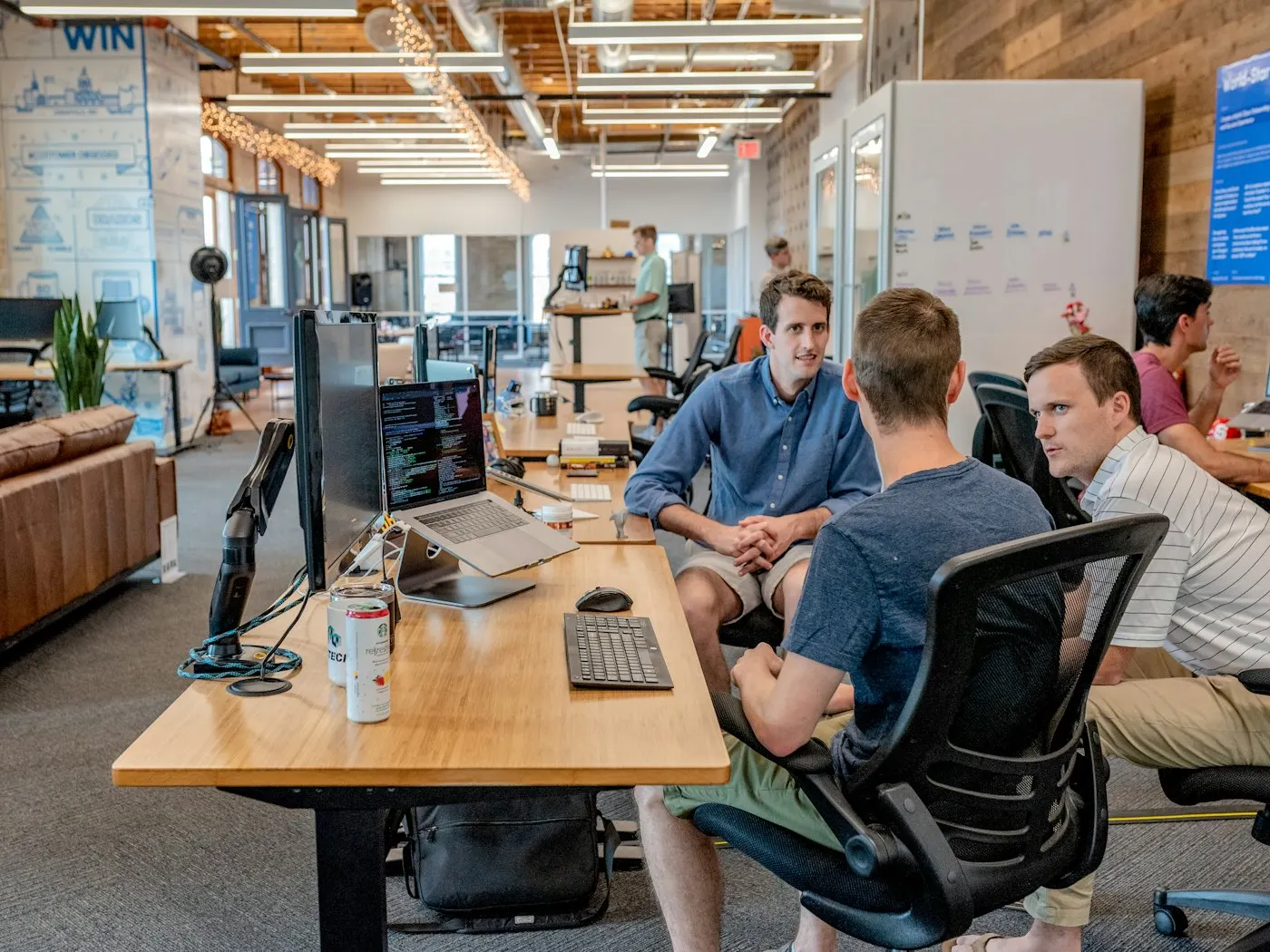 Colleagues talking across a desk beside a laptop